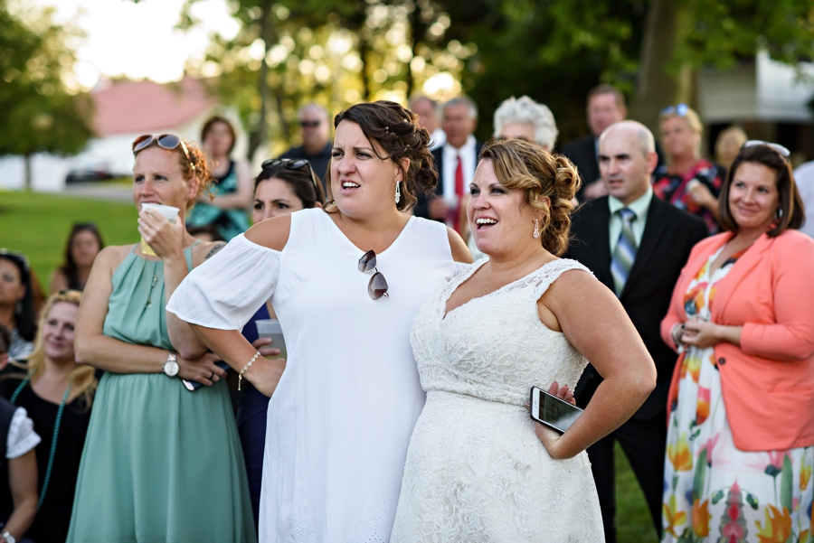 A newly married lesbian couple watching a slideshow at their wedding.